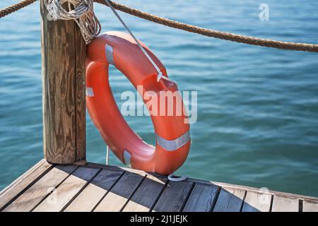 Red lifebuoy near the fence on the wooden pier.  Stock Photo