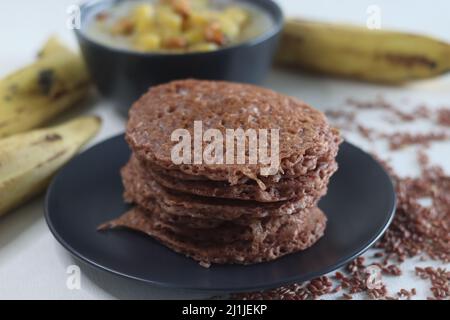 Red rice pancakes. Pancakes made of a fermented batter of red rice and coconut. Also called Red rice appam in Kerala. Served with Ripe plantain stew. Stock Photo