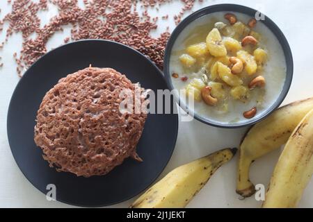 Red rice pancakes. Pancakes made of a fermented batter of red rice and coconut. Also called Red rice appam in Kerala. Served with Ripe plantain stew. Stock Photo