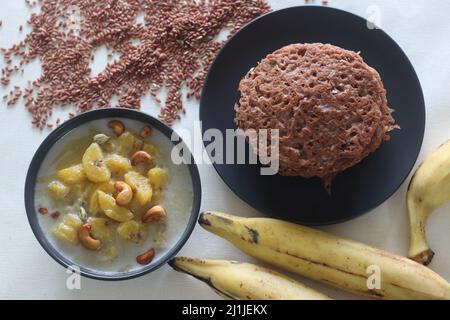 Red rice pancakes. Pancakes made of a fermented batter of red rice and coconut. Also called Red rice appam in Kerala. Served with Ripe plantain stew. Stock Photo