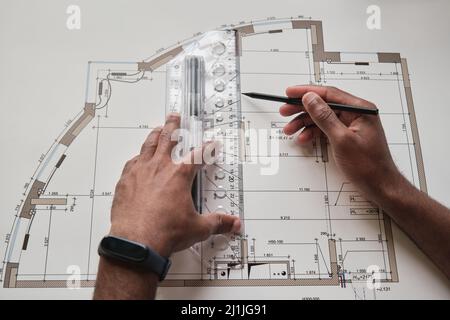 Close-up of Black hands drawing floor plan using pencil and engineering ruler Stock Photo