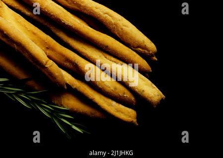 Close-up of Italian breadsticks Grissini with rosemary herbs on a black background Stock Photo