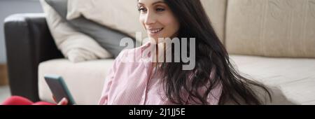 Young woman sitting on the floor and looking at the phone Stock Photo