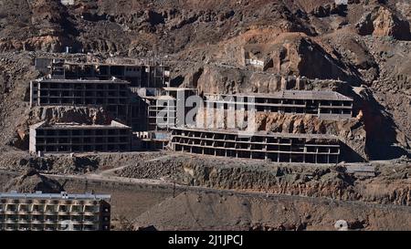 View of unfinished ruined hotel building in village Taurito, southern Gran Canaria, Spain, located in a valley between rocks on sunny day. Stock Photo