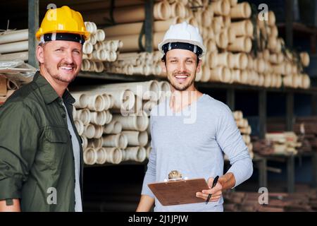 Im the man with the plan. Cropped portrait of two male construction workers looking over some paperwork while standing in an industrial warehouse. Stock Photo