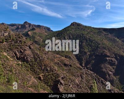 Beautiful view of the rugged mountains near road GC-605 in the center of island Gran Canaria, Spain with hiking path and pine trees on the slopes. Stock Photo