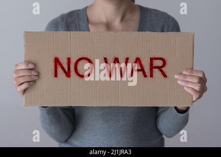 A woman holds sign 'NO WAR' in front her face Stock Photo