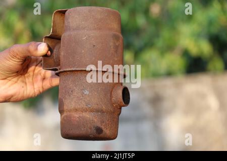 Rusty metal chimney of an old diesel engine for releasing combustion gases held in hand on a natural background Stock Photo