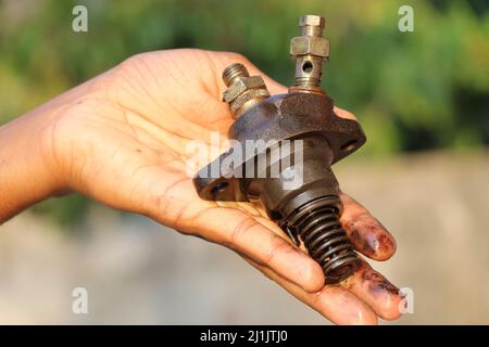 Diesel Fuel injector from an old diesel engine held in hand with a view of its parts Stock Photo