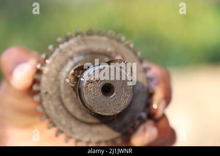 Focus on Tip of the Camshaft sprocket part of an internal combustion engine held in hand, Repairing an engine concept Stock Photo
