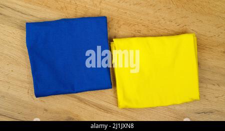 Close up photo of textile square shape two colors blue and yellow on the table, flag of Ukraine concept. Stock Photo