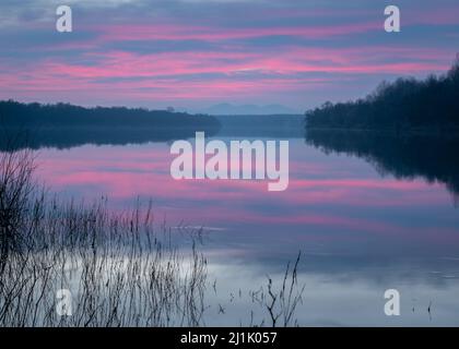 Peaceful atmospheric landscape with pastel colors, Sava river at twilight, forested banks lead to distant mountain silhouette in haze, calm nature and Stock Photo
