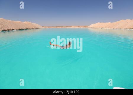 Siwa, Egypt. 26th Mar, 2022. A man floats on a salt lake at Siwa Oasis in Matrouh Governorate, Egypt, on March 26, 2022. Siwa Oasis lies in Egypt's western desert, some 800 kilometers from Cairo. There are many natural salt lakes on which people can float naturally. Credit: Sui Xiankai/Xinhua/Alamy Live News Stock Photo