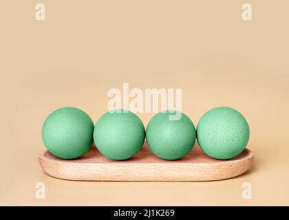 Green painted Easter eggs on wood board on beige background with copy space for text. High quality photo Stock Photo