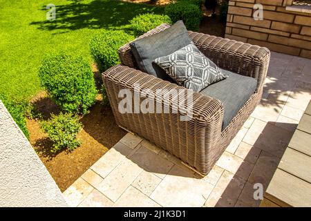 Large Wicker Arm Chair On Outdoor Patio Stock Photo