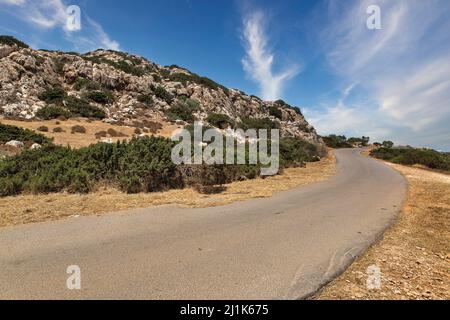 Landscape road to Cape Greco peninsula, Cyprus. It is mountainous peninsula with a national park, rock paths, a turquoise lagoon and a natural stone b Stock Photo