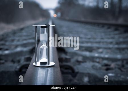 an hourglass stands on the rails of the railroad Stock Photo