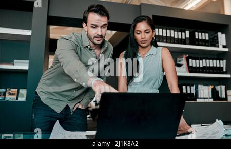 Lets discuss this section. Shot of two young businesspeople discussing something on a laptop. Stock Photo