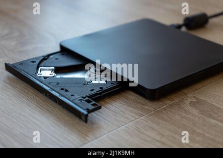 An external black DVD-ROM sitting on a wooden table Stock Photo
