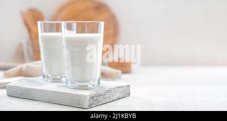 Milk in two transparent glasses on a white background. Side view, copy space. Stock Photo