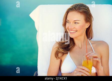 Poolside refreshments. Shot of an attractive young woman enjoying a poolside drink. Stock Photo