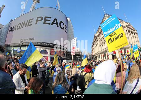 London, UK. 26th Mar, 2022. Participants in the London Stands with Ukraine march in London passing Piccadilly Circus where Yoko Ono's Imagine Peace was displayed in support of Ukraine against the Russian invasion and war Credit: Paul Brown/Alamy Live News Stock Photo
