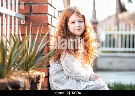 Portrait of a cute, little, ginger girl in white dress Stock Photo