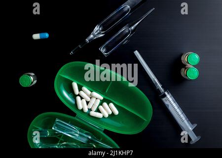 Medical accessories, syringe, pills, capsules, ampoules, black background. Stock Photo