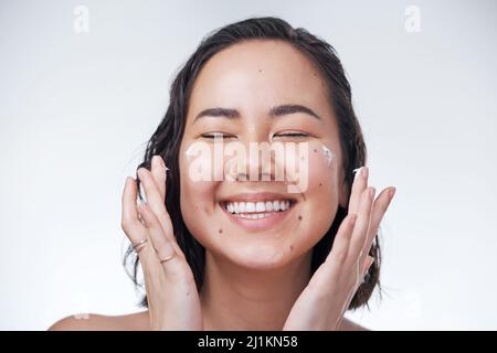 Our skin needs a little extra TLC. Cropped shot of a beautiful young woman applying moisturiser to her face. Stock Photo