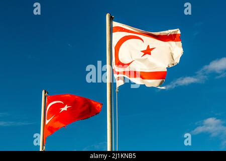 The Northern Cyprus flag always flies next to the Turkish flag in the Turkish Republic of Northern Cyprus (TRNC); this flag, flying over Girne, is already visibly tattered by the wind. Stock Photo