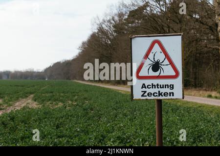 Warning sign against ticks in a forest area in Germany near Petershagen. Stock Photo