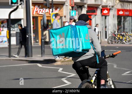 Cardiff, Wales - March 2022: Cycle courier for the Deliveroo food delivery service riding through the city centre Stock Photo