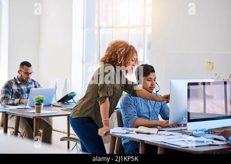 When the customer calls, direct them here. Shot of a young phone operator speaking with a coworker at his desk. Stock Photo