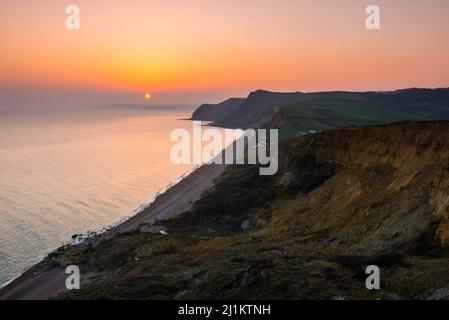 Eype, Dorset, UK. 26th March 2022. UK Weather. The sky glows orange at ...