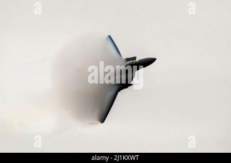 USAF McDonnell Douglas F-15 Eagle fighter jet plane at speed with condensation vapour forming clouds of moisture on the wings. Pulling hard turn Stock Photo