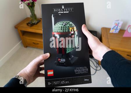A man in his forties holding a box of 18+ lego for the scale model head of the bounty hunter Boba Fett from Star Wars. UK. Theme: adult hobbies Stock Photo