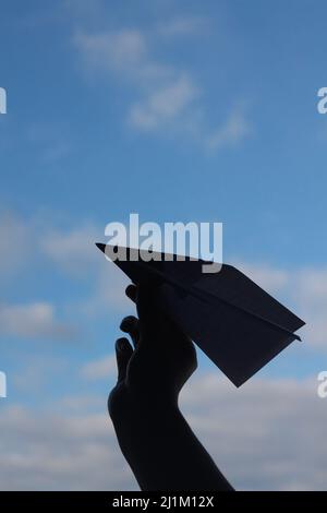 Hand throwing paper plane to blue sky, clear blue sky, sky background, paper plane in blue sky Stock Photo