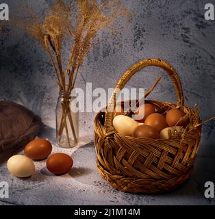 Easter composition. Basket with eggs, several eggs bouquet of dried flowers on a gray background Stock Photo