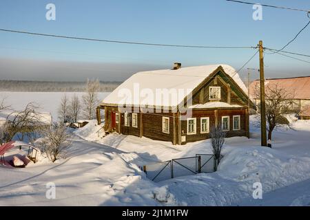 Snow-covered village in winter Russia, wooden country house on roof of which snow lies. Stock Photo
