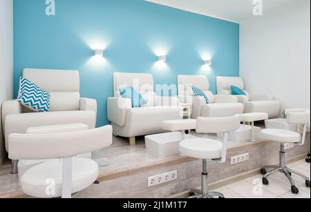 Nail salon bright interior, modern pedicure armchairs in manicure shop or spa room. Inside beauty studio with blue and white design. Clean empty trend Stock Photo