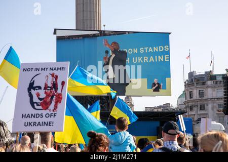 Trafalgar Square, London, UK. 26 March 2022. Under the banner ‘London stands with Ukraine’ begins a solidarity march from Park Lane to Trafalgar Square.  Hundreds of demonstrators converge on Trafalgar Square for a vigil to send a unified message of support to the Ukrainian people. Labour politicians and other speakers deliver on stage a strong message to the crowd. David Lammy Labour MP on screen addressing the crowd. Stock Photo