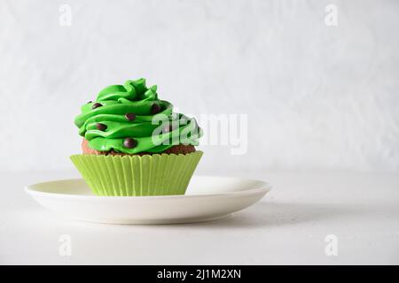 Homemade chocolate cupcake with green whipped cream and chocolate sprinkles on white background. Close up. Birthday celebration. Stock Photo