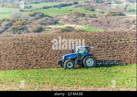 Reenascreena, West Cork, Ireland. 26th Mar, 2022. Reenascreena based farmer, Cian Daly who is in partnership with his grandfather Michael, ploughs a field to plant wheat on a warm, sunny day in West Cork. Cian and Michael farm beef and dairy on 160 acres and Cian was using a New Holland T6050 tractor and Fiskars 5 furrow plough to prepare the field for planting. Credit: AG News/Alamy Live News Stock Photo