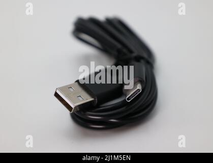 A cable wrapped up in front of a white background. The cable is USB C but is lower speed. Stock Photo