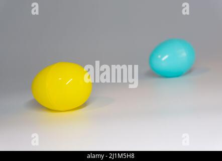 Plastic eggs, closed with the yellow egg in front of the blue egg. White background. Stock Photo