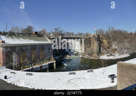A panoramic view to a walking alley with benches looking at the river and a hanging bridge in the wintertime. Stock Photo