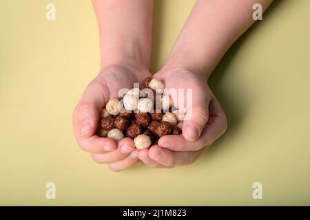 children's hands hold chocolate and white corn balls Stock Photo