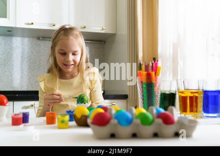 A smile girl paints easter eggs. Stock Photo
