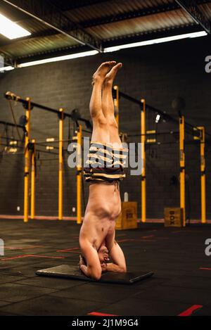 Man without t-shirt practicing yoga on a gym Stock Photo