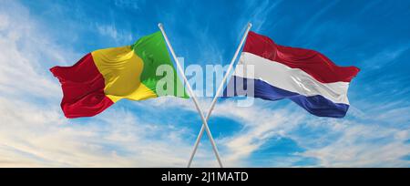 two crossed flags Mali and Netherland waving in wind at cloudy sky ...